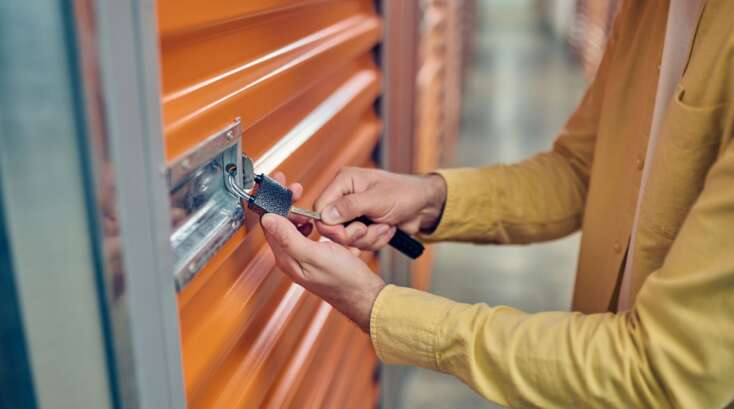 Person unlocking an orange storage unit door.