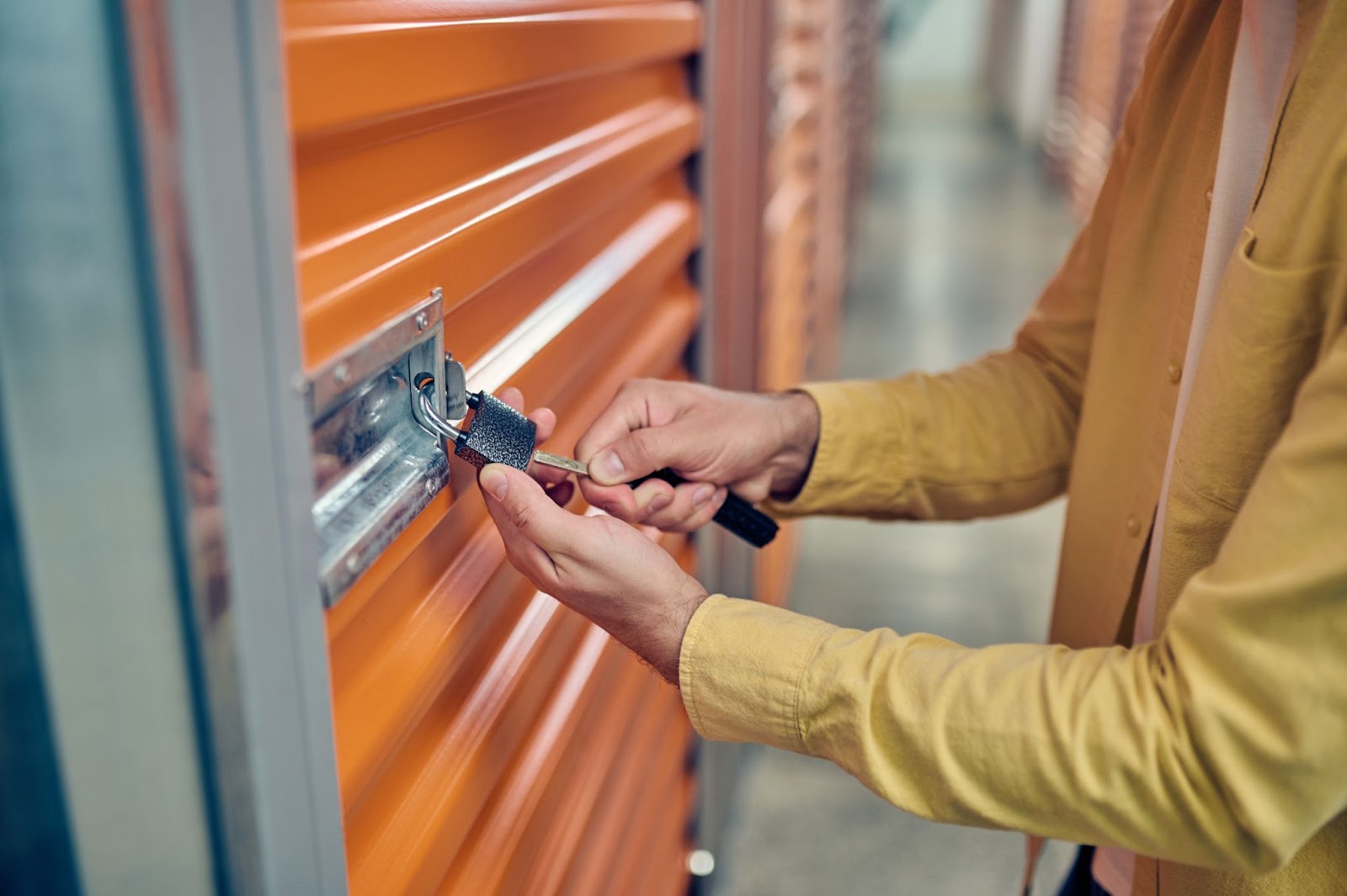 Person unlocking an orange storage unit door.