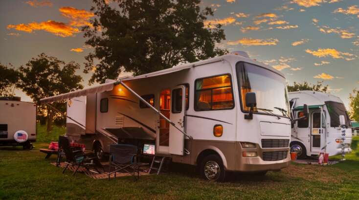 RV campsite with chairs and sunset sky.