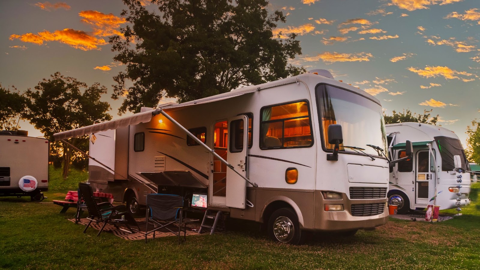 RV campsite with chairs and sunset sky.