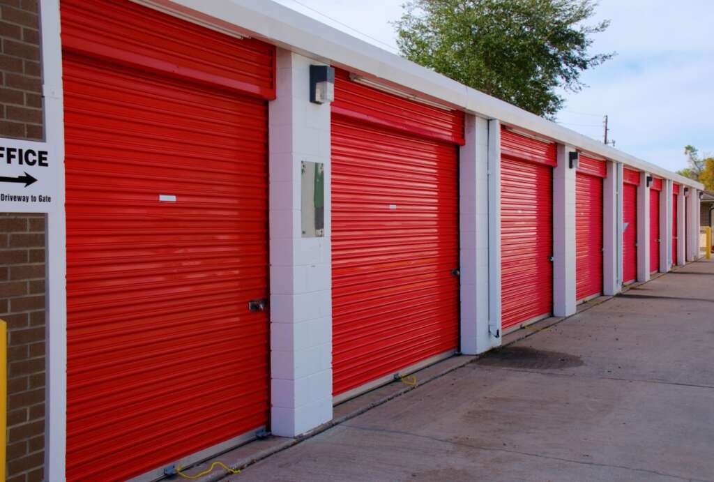 Row of red storage unit doors with office sign.