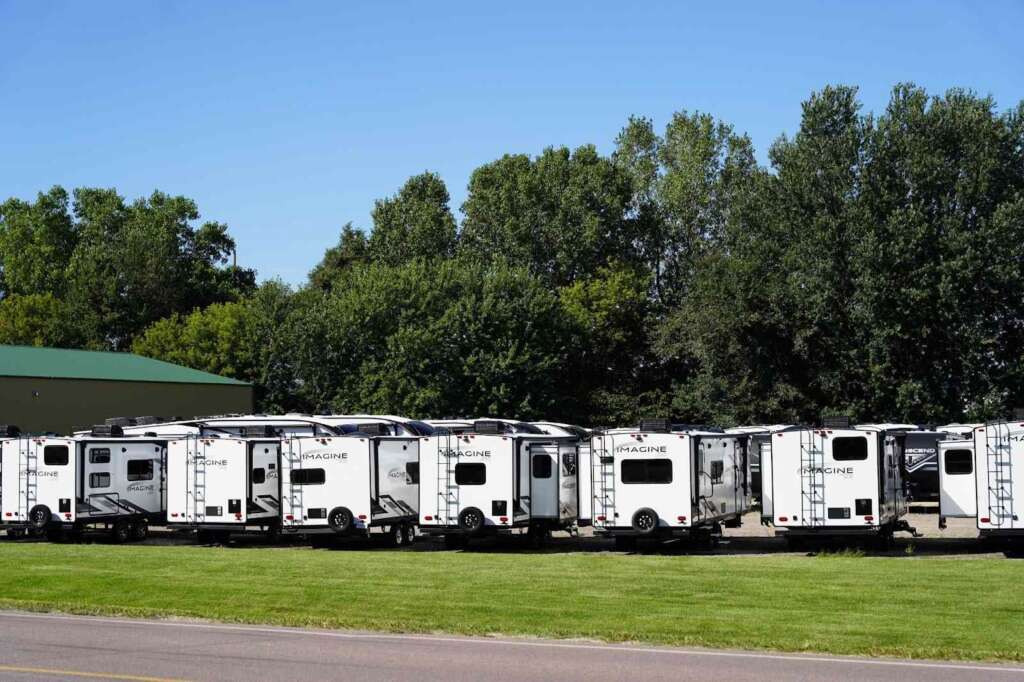 Row of white Imagine trailers parked on grass.