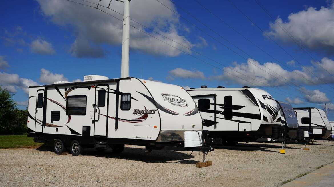 Travel trailers parked under a partly cloudy sky near a utility pole.
