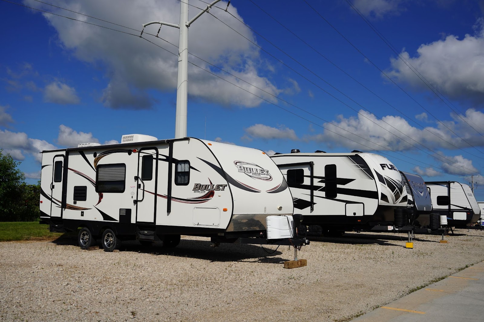 Travel trailers parked under a partly cloudy sky near a utility pole.