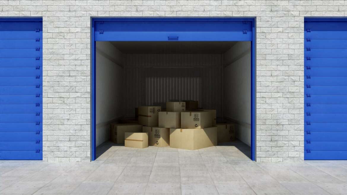An open storage unit filled with stacked boxes and a partially open door, showcasing its contents.