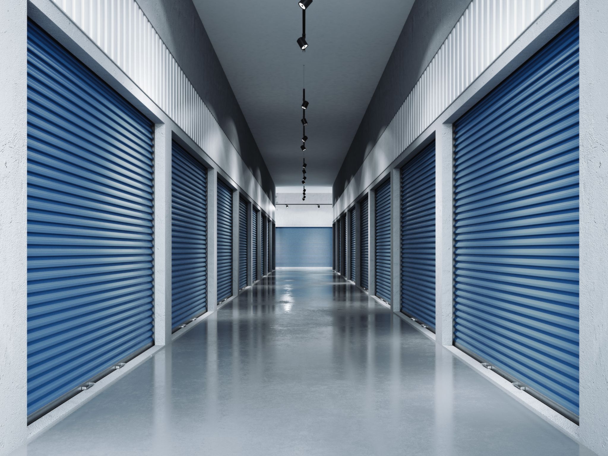 An indoor self-storage facility corridor with blue roll-up doors.