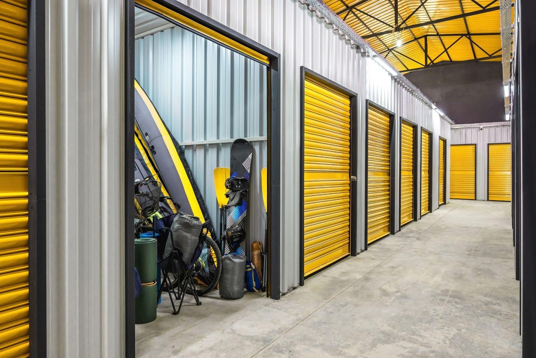A storage facility with yellow doors prominently displaying a surfboard beside it